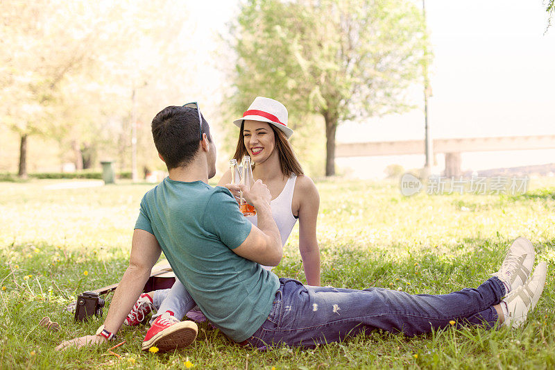 微笑的情侣在公园里祝酒。