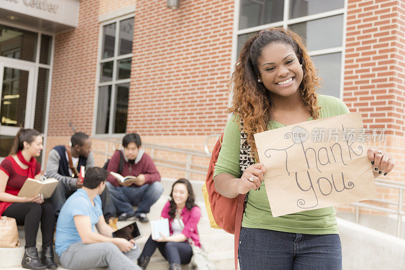 教育背景:非洲裔大学生举着“谢谢”的牌子。