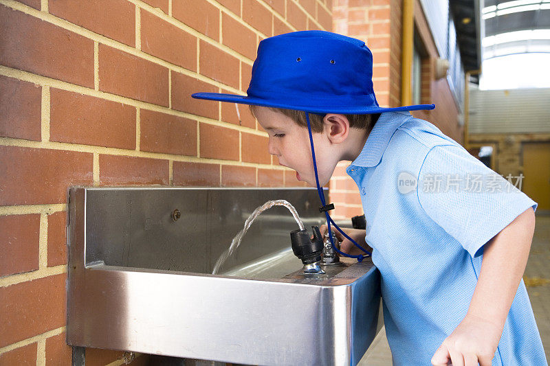 一个从饮水机里喝水的男生