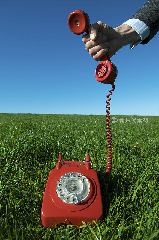 商务手持红色电话户外亮绿色草地