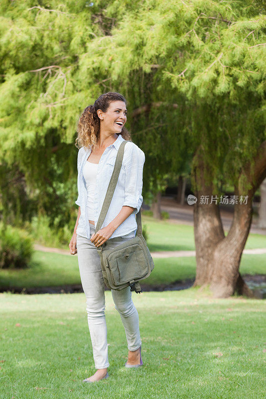 漂亮女人背着背包在公园里走来走去