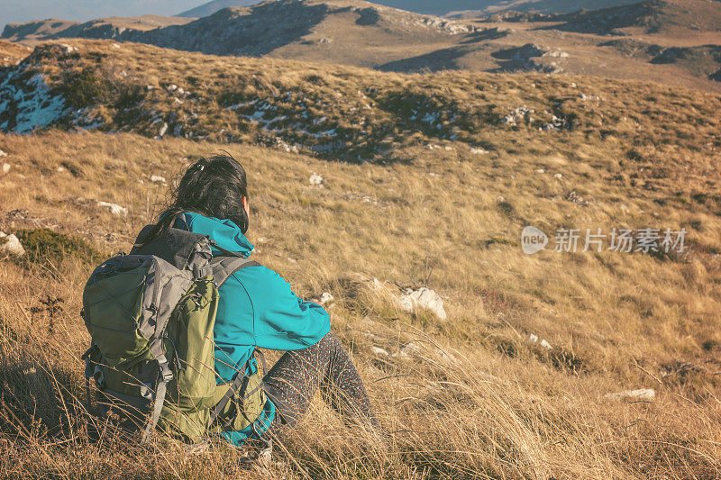 女孩徒步旅行者坐在美丽的山上