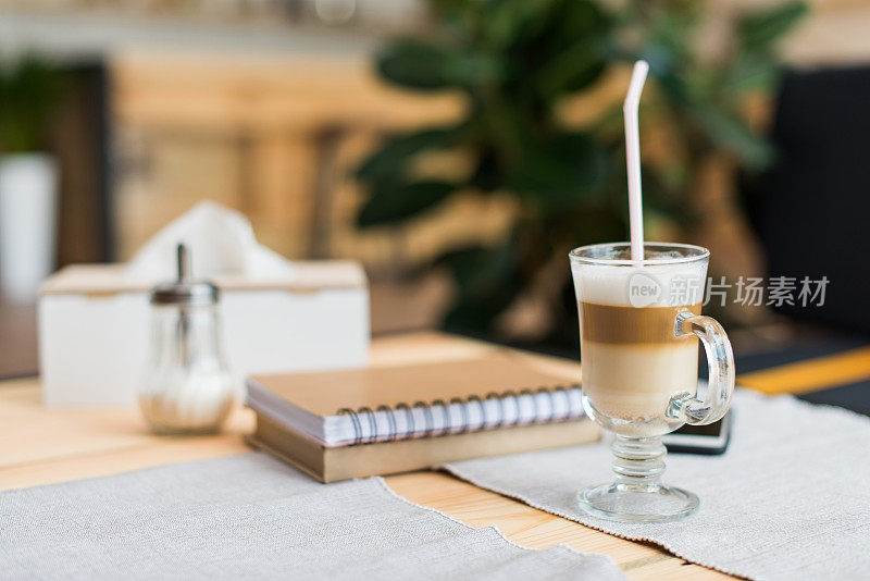 近距离观看咖啡拿铁，书和笔记本上的桌子在咖啡馆