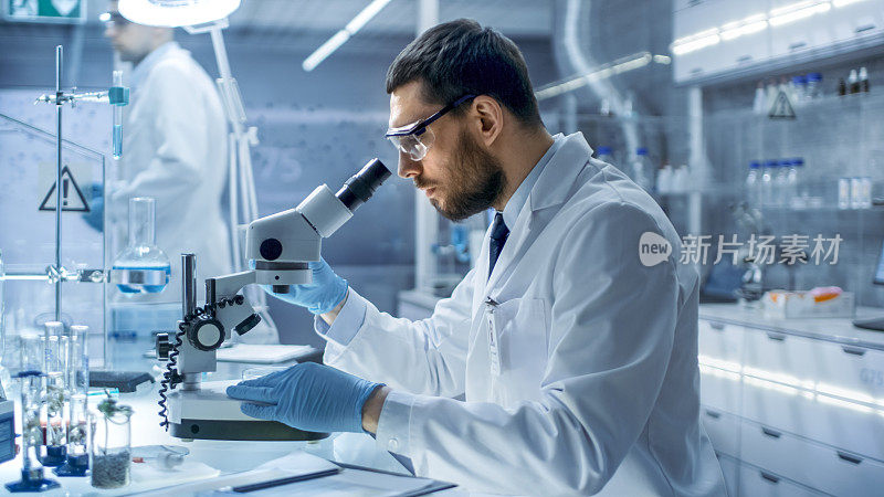 在现代实验室研究中，科学家用有机材料进行实验。他在看显微镜。