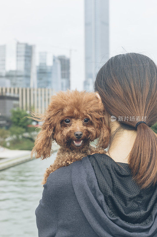 一个女人抱着她的宠物站在桥上看风景