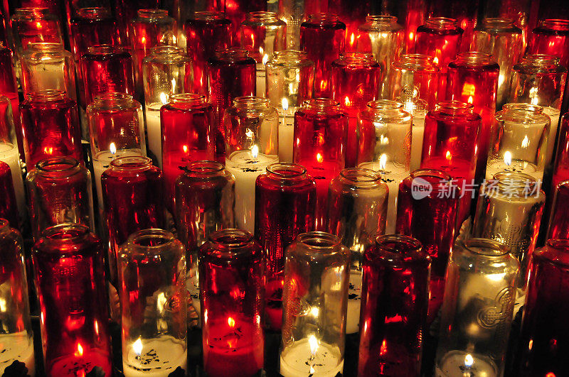 燃烧的蜡烛在透明和红色的小瓶。前视图