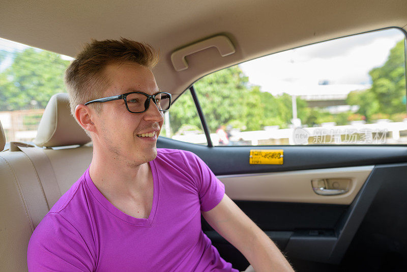 车上有一个年轻英俊的男子的肖像，他穿着紫色的衬衫，戴着眼镜