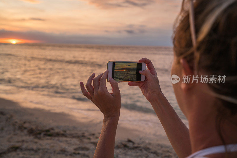 年轻女子用手机拍摄日落，印度尼西亚