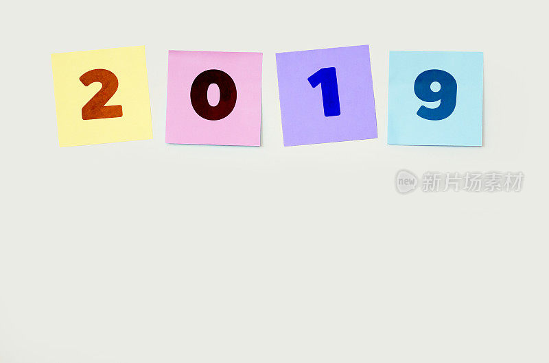 帖子贴在一面白色的墙上，上面写着2019(新年快乐2019决心概念)