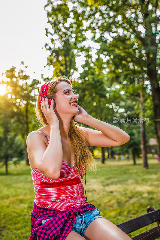 年轻女孩在城市公园里听音乐