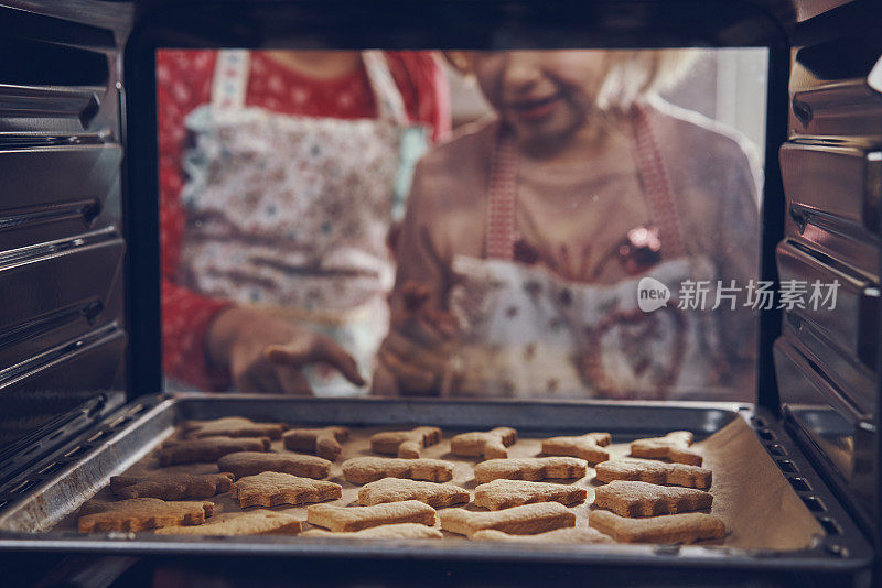 等待圣诞饼干在烤箱里烤的小女孩