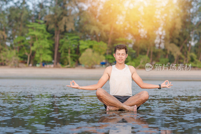 年轻的亚洲男子在日落海滩做瑜伽运动