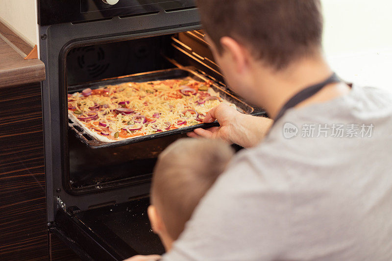 爸爸和儿子在厨房里愉快地做披萨