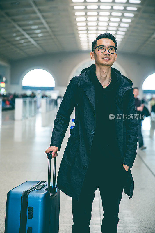 一个年轻人拿着行李走在机场