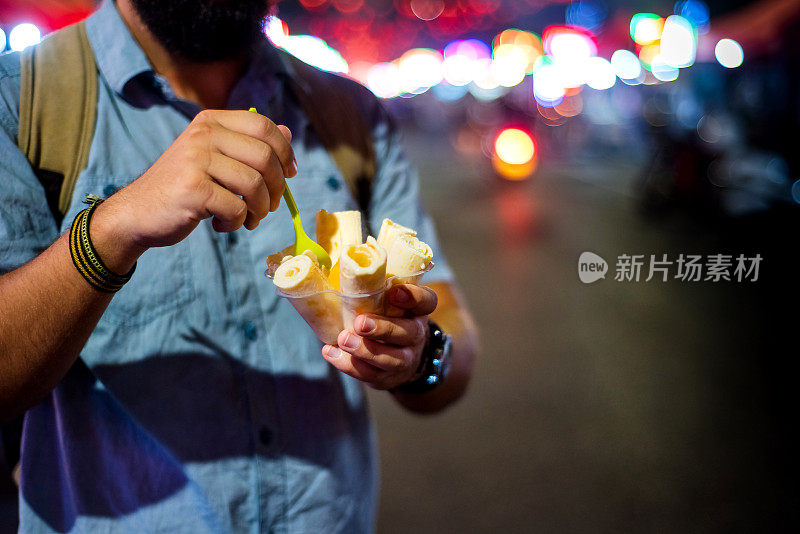 在夜市吃冰淇淋卷的男人