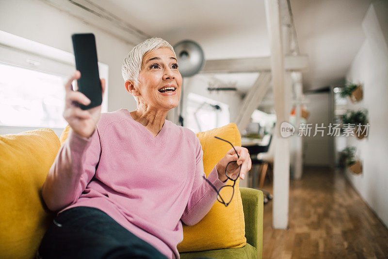 成熟的女人坐在沙发上拿着手机