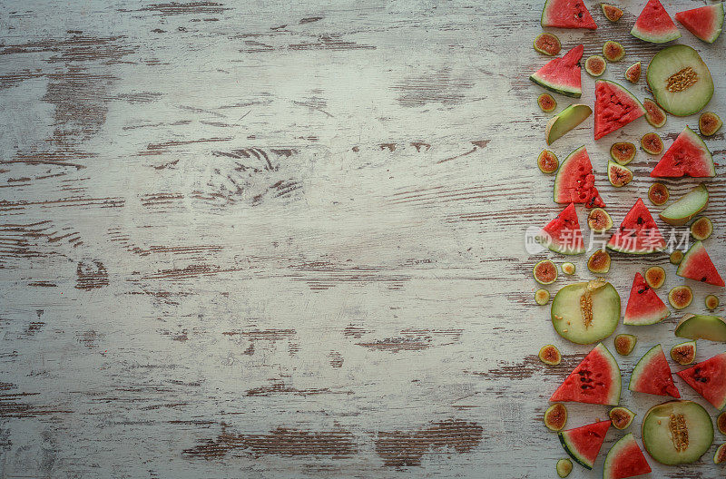 切成薄片的西瓜、甜瓜、无花果排列在木质背景上