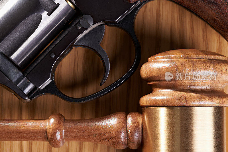 枪支管制立法概念:木桌上的木槌和手枪特写