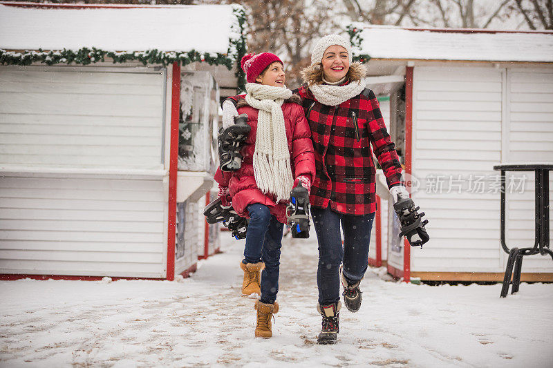 愉快的母亲和女儿在滑冰后蹦蹦跳跳，面带微笑