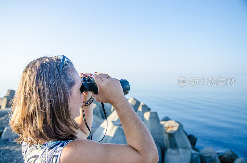 用双筒望远镜看海的女人