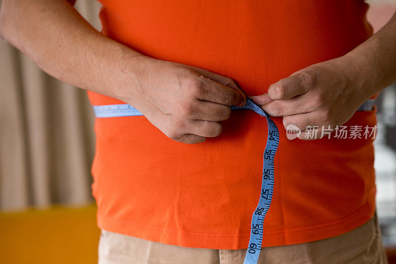 一个肥胖的男人在测量他的肚子