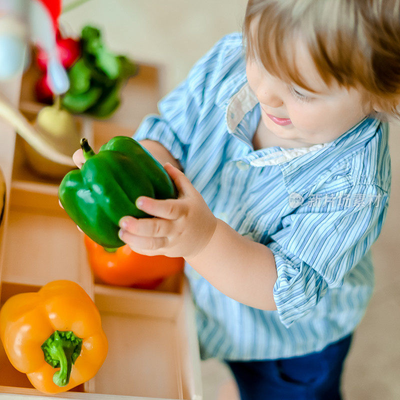 小男孩带着健康的水果和蔬菜在农场小摊上玩