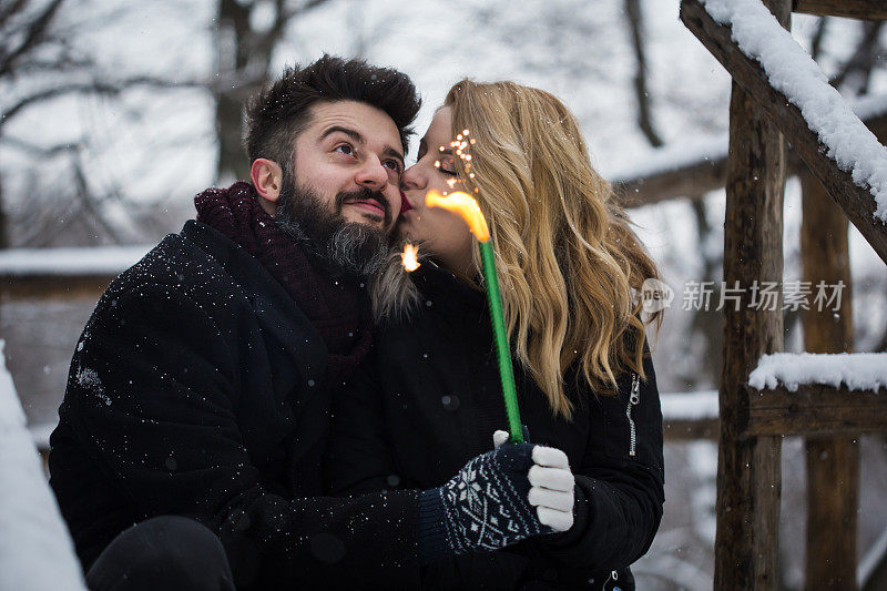 夫妇拿着烟花。一对年轻夫妇在冬天的森林里拿着火花。快乐微笑的夫妇与节日烟花庆祝圣诞户外