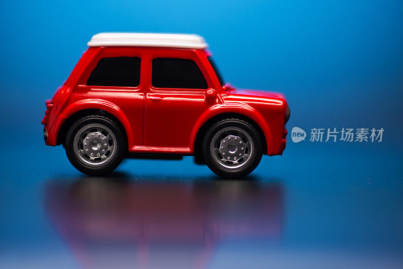 侧侧;蓝色背景上的红色小玩具汽车模型。