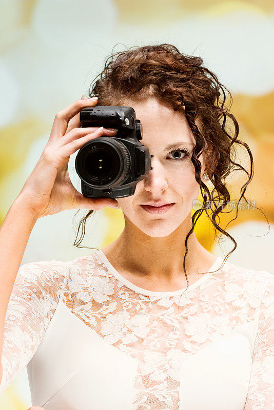 白种人年轻女性摄影师在散焦背景穿着裙子和拿着相机