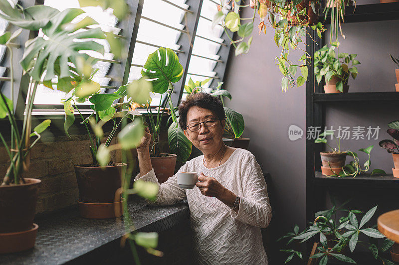 一位活跃的亚洲华裔年长女性正在办公室休息室喝咖啡休息