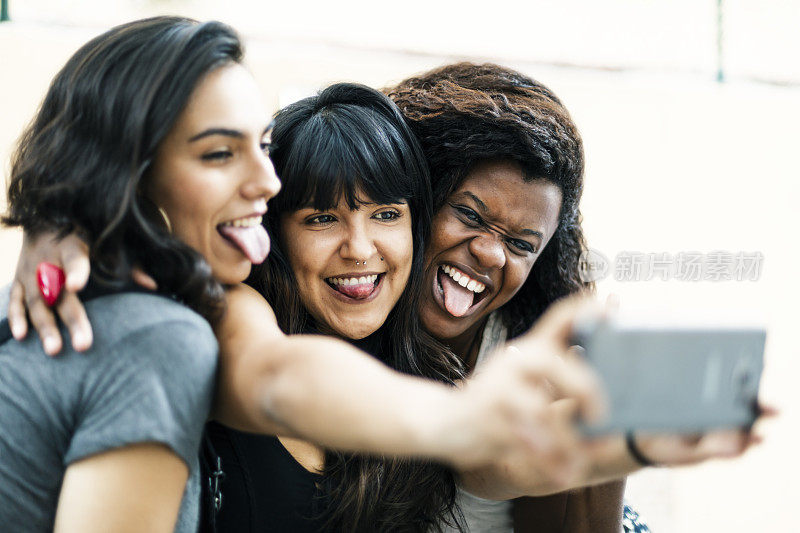 三个年轻漂亮的女人伸出舌头自拍。