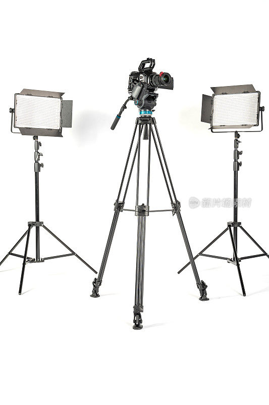 专业电影摄像机在一个相机三脚架和两个专业照明灯具在白色工作室背景