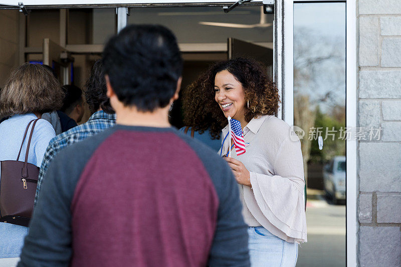 当选民走进投票站时，微笑的志愿者为他们开门