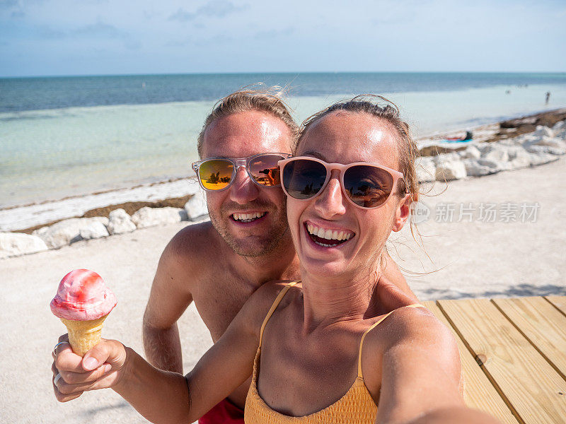 一对情侣在海滩上吃冰淇淋的自拍