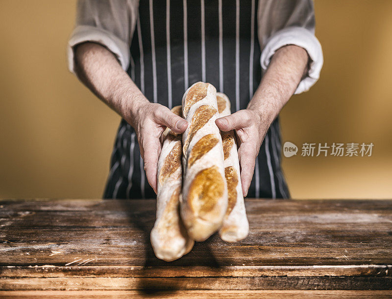 面包师在面包店的木桌上提供法棍面包