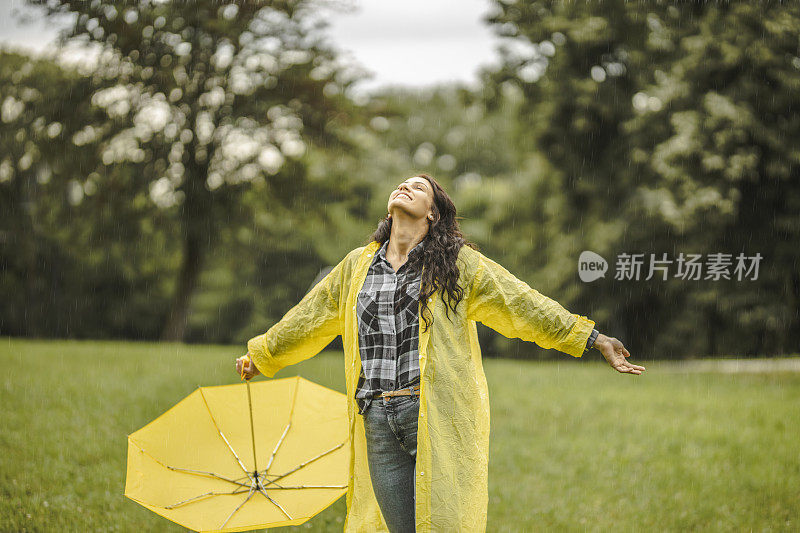 拿着黄伞，穿着黄雨衣，享受着雨的女人