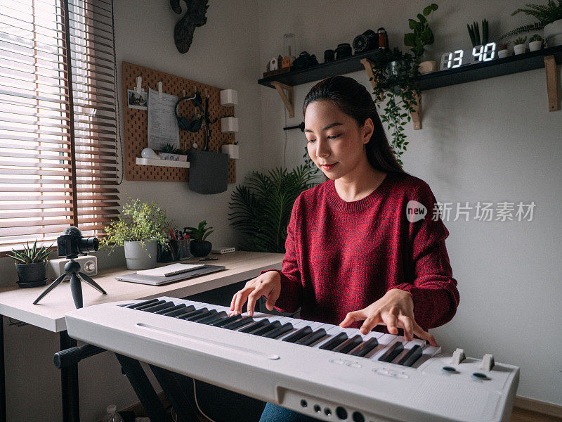 年轻女子在网上用在家视频教程上钢琴课。