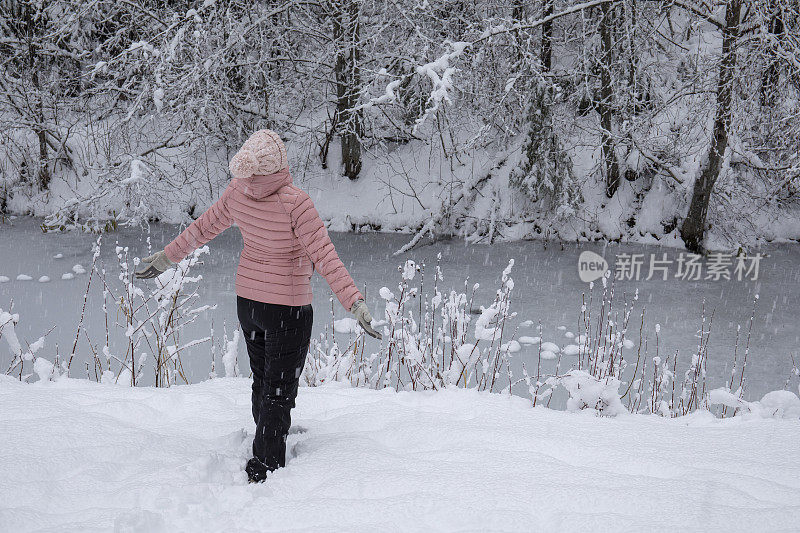 女徒步旅行者在白雪覆盖的河岸放松