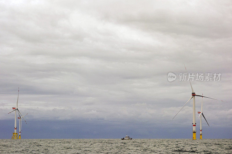 船、码头之间是巨大的海上8MW的风力发电机在波涛汹涌的海面上与戏剧性的天空