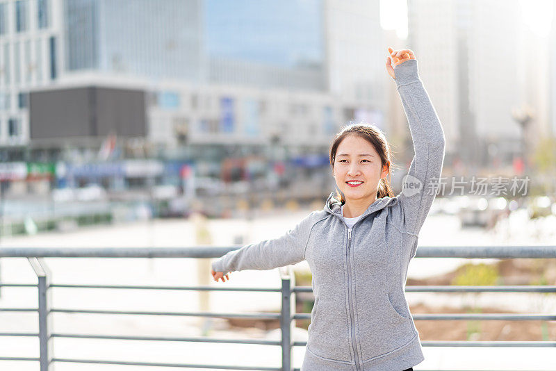 亚洲年轻女子站和伸展后，在城市跑步