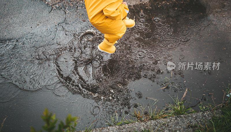 小男孩在雨中玩耍，跳进水里画画