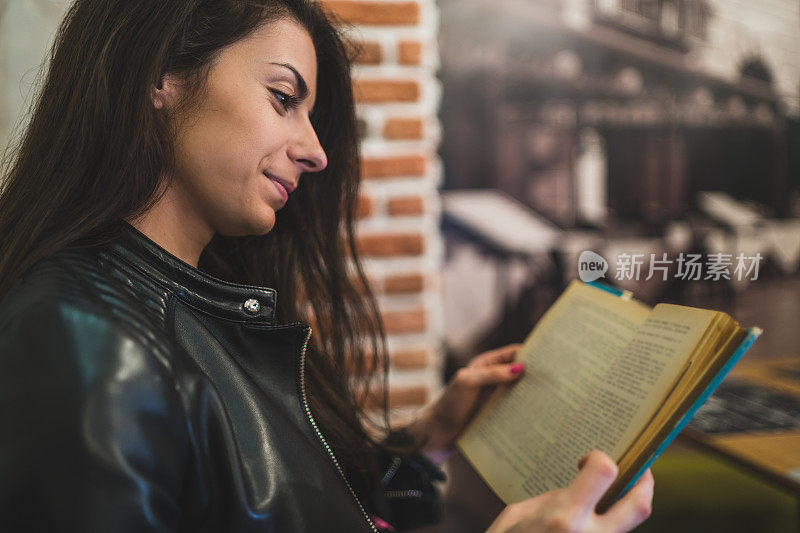 美丽的年轻女子放松和阅读在咖啡店与副本空间的散焦背景