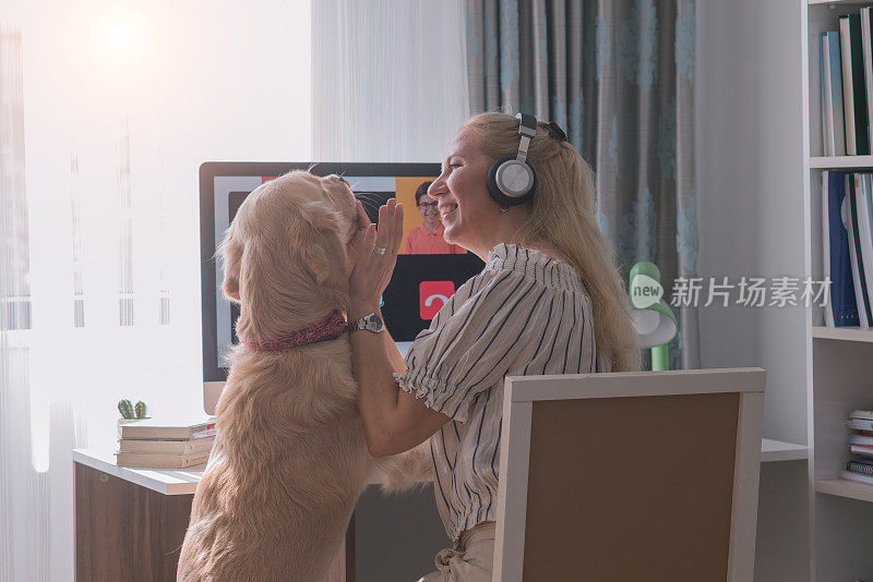 快乐的母亲和狗挥手与家人视频通话。