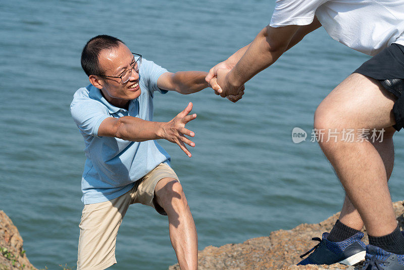 两个游客在海边互相帮助。