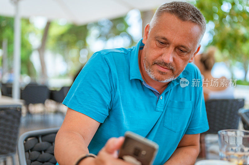 一个成熟的男人在酒吧外面用手机