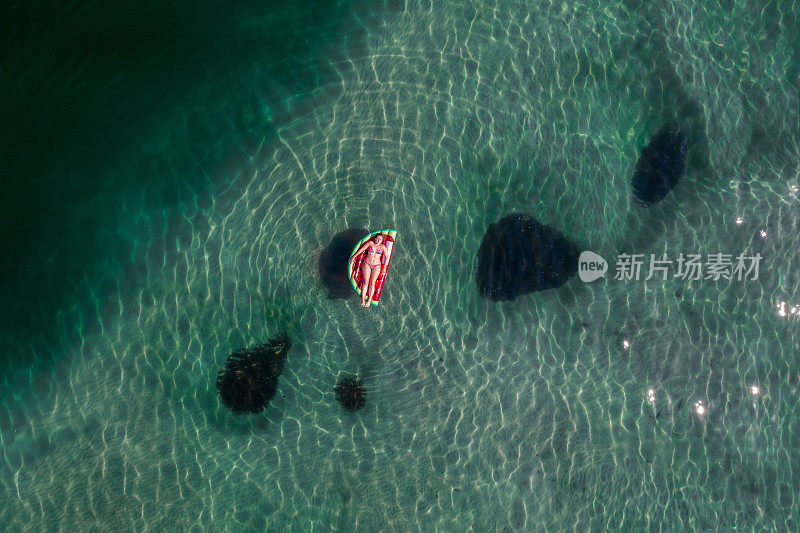 鸟瞰图上的女人漂浮在湖上充气床垫日光浴