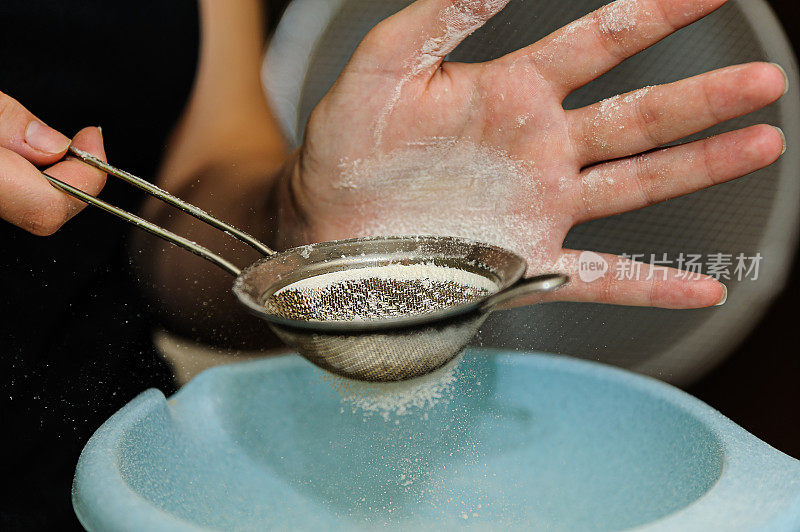 一个女厨师把面粉倒进碗里以便做一个面团的特写照片。