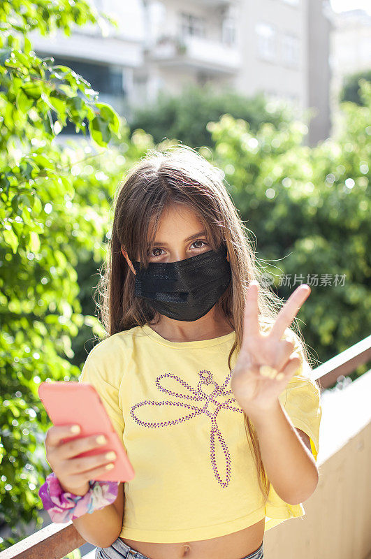 一个女孩的肖像戴着防护面具和手机