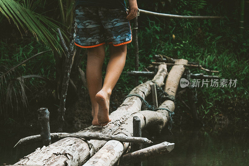 一个孩子在丛林里走过桥