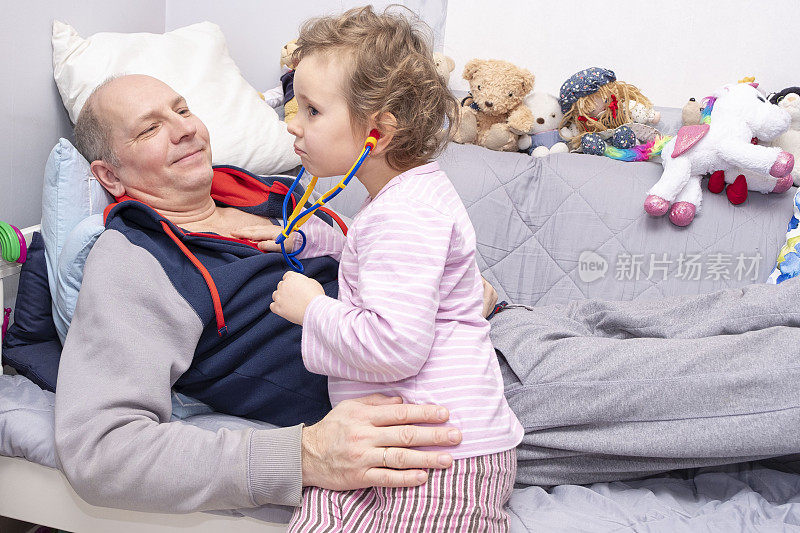 家庭的乐趣。一男一女，5岁白人，在医院里玩。女儿用听诊器听父亲说话。